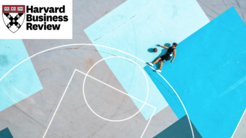 Aerial view of a person playing basketball on a colorful outdoor court painted in shades of blue. The Harvard Business Review logo is placed in the top left corner